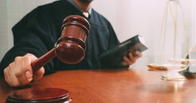 justice and law concept.Male judge in a courtroom with the gavel and working with smart phone and brass scale on wood table