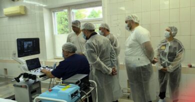 Хирурги наблюдают за исследованием вен пациента с помощью ультразвукового аппарата.