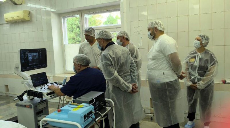 Хирурги наблюдают за исследованием вен пациента с помощью ультразвукового аппарата.