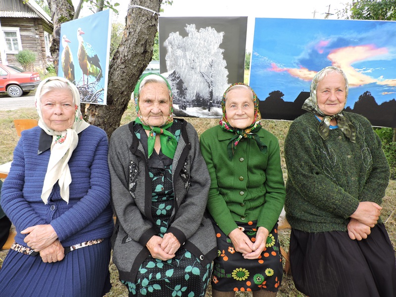 Жыхаркі вёскі (сястра Леакадзія другая злева) на фоне карцін фотамастака.